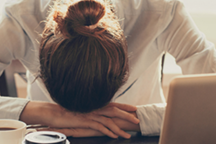 Photo: Stressed out woman resting her head on desk