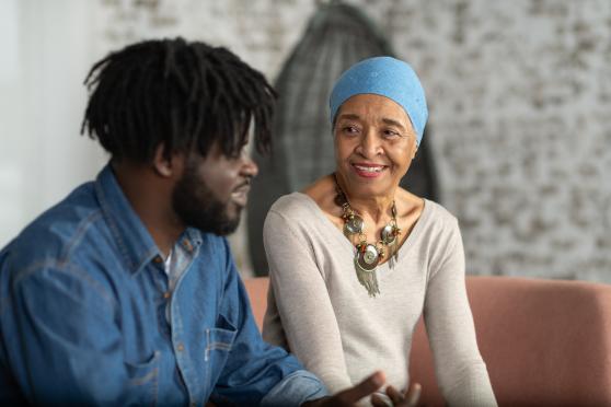 A woman with ovarian cancer speaks to a man about her condition. She is wearing a blue head scarf.