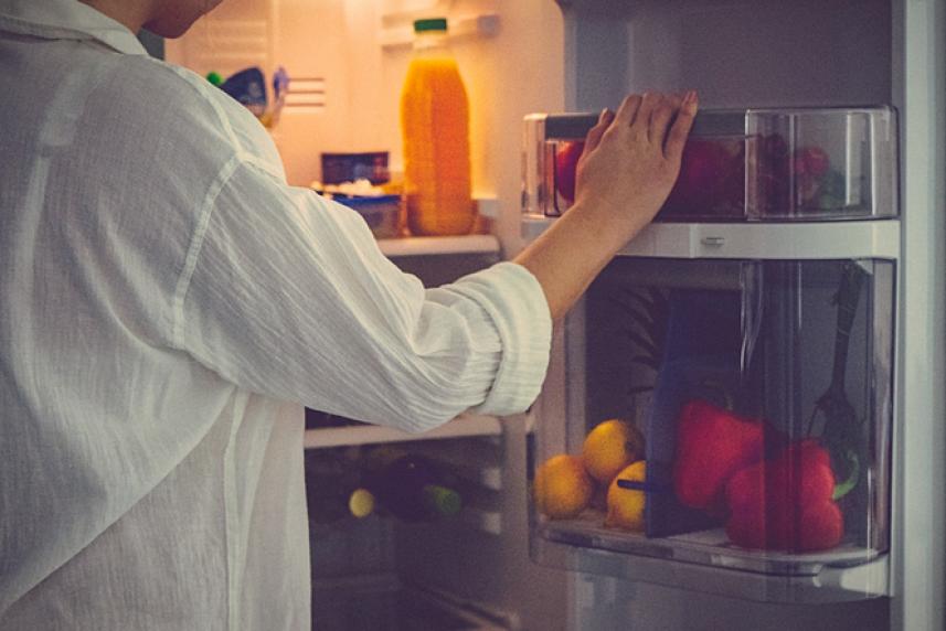 Photo: Adult reaching into fridge at night