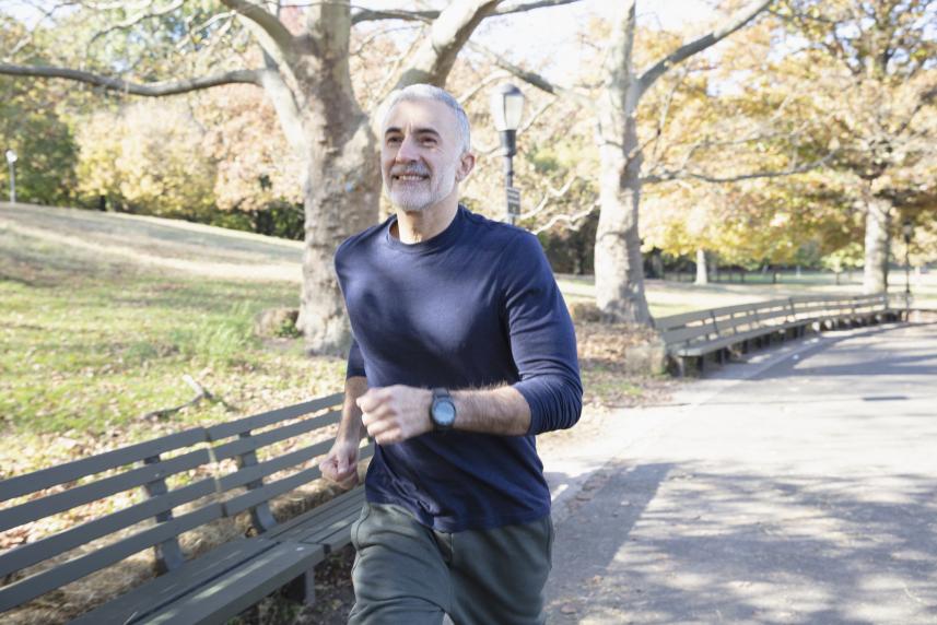 A healthy man running on a paved path in a park