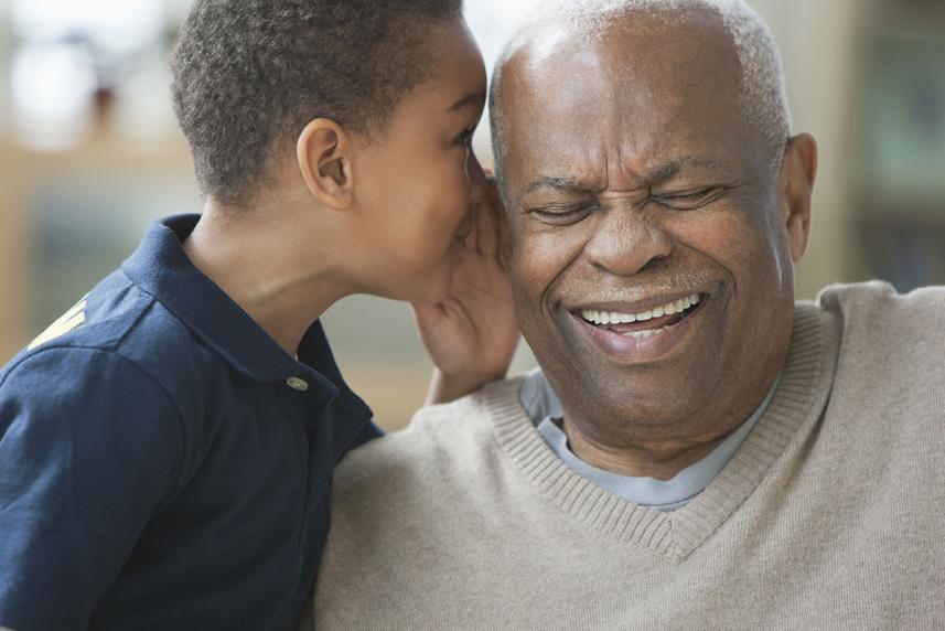 Young boy whispers in older man's ear