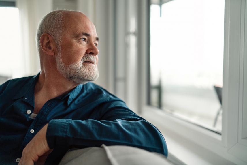 A man looks pensively out the window after receiving a prostate cancer diagnosis.