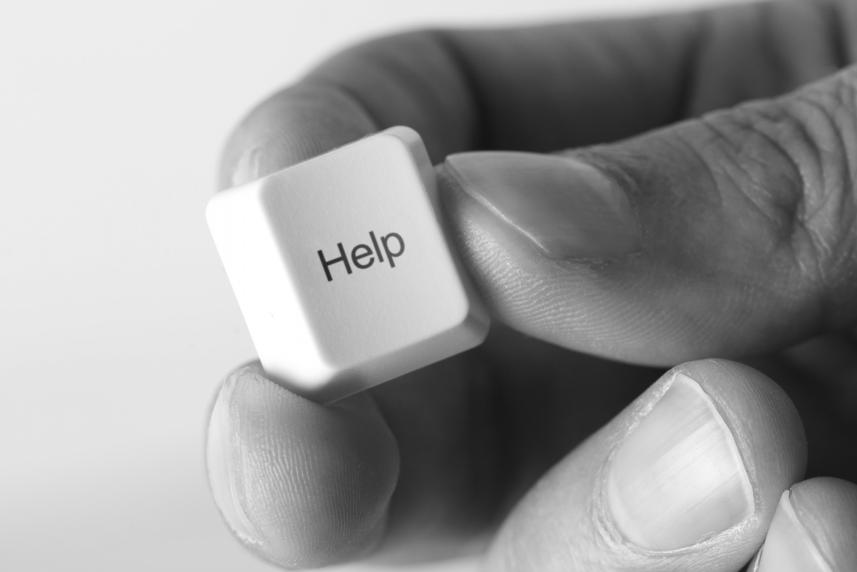 Photo: Black & white photo of man's hand holding a computer key "Help".