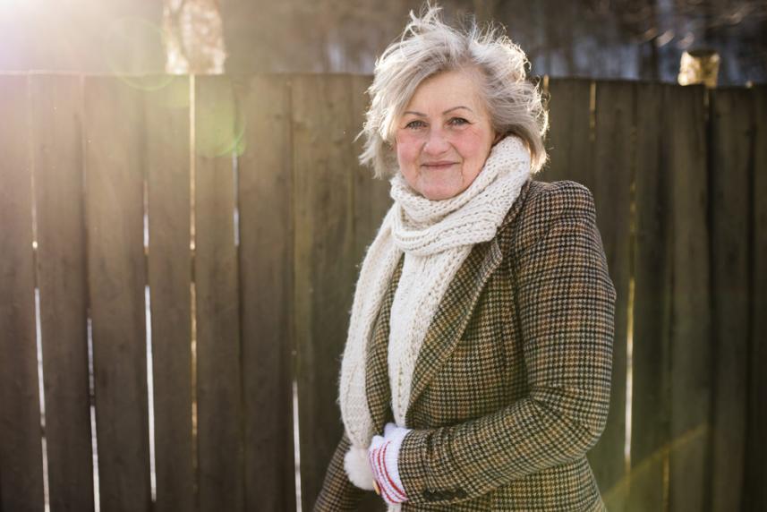 Photo: Smiling mature woman outdoors in cold weather, dressed in warm clothes.
