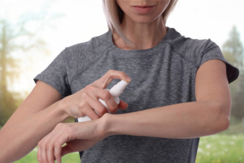 woman spraying bug repellent on arm