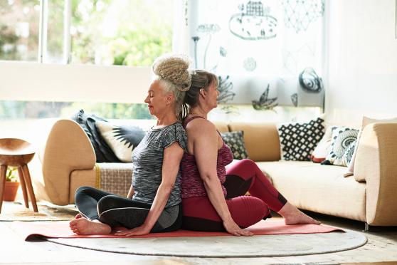 Two women, back to back on a yoga mat