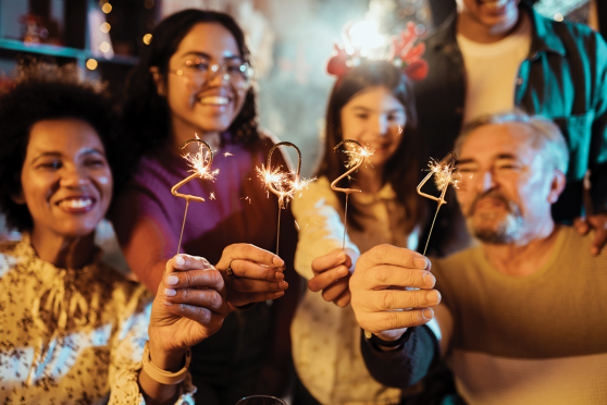 A group of people holding up sparklers that read out "2024"