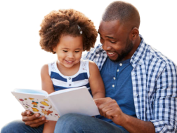 A young child sitting with their parent reading a bookk