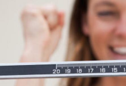 Photo: Woman on a scale excited about weight loss results