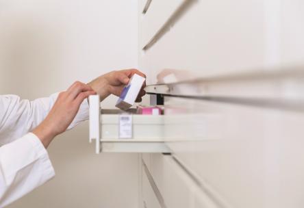 Doctor grabbing medicine box from cabinet