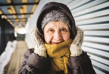 Woman wrapped up in coat, scarf, and mittens.