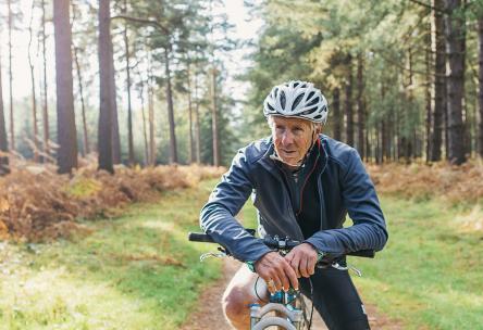 Older male biking in forest