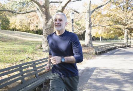 A healthy man running on a paved path in a park