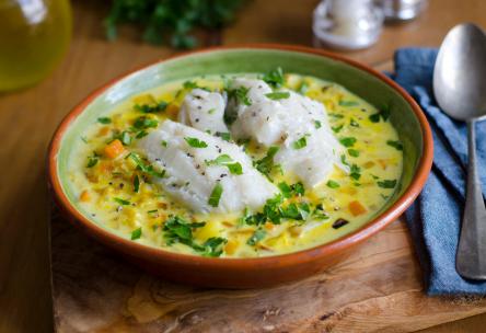 Photo: Bowl of creamy fish and chive chowder, with rustic table setting.