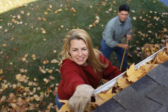 Husband and wife cleaning leaves out of their gutters