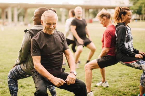 Smiling man at an outdoor group exercise class. 